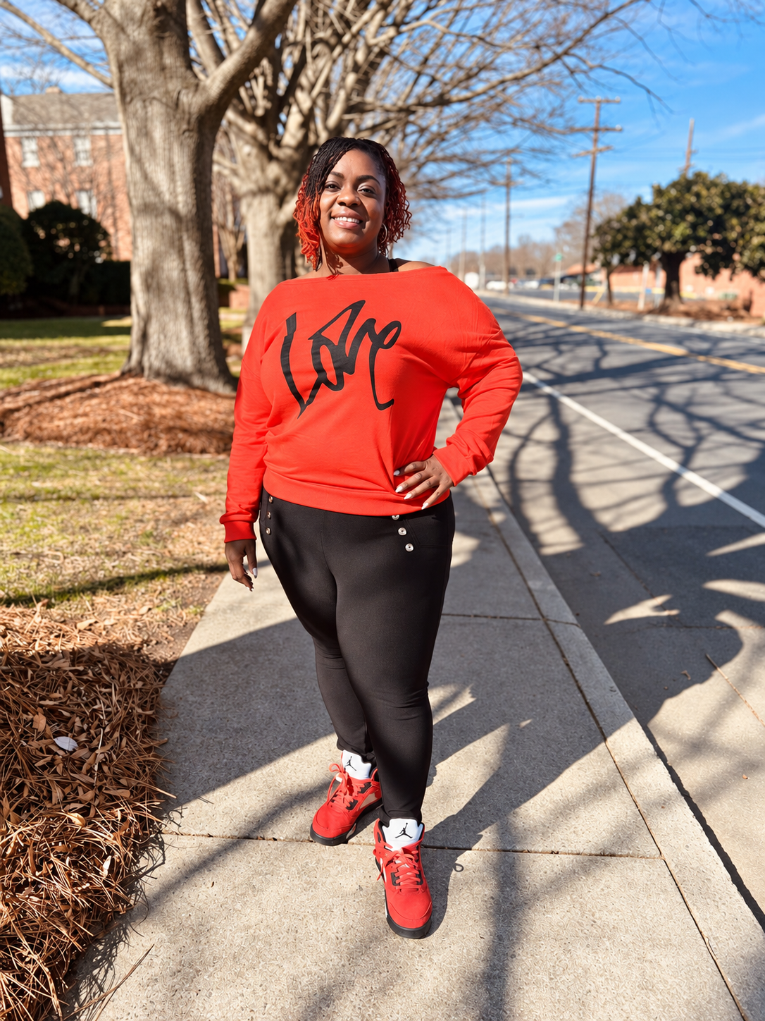 Angenette Burns standing outdoors in an orange Love sweatshirt